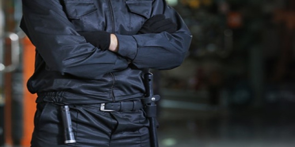 A security guard in uniform with crossed arms and equipped gear, emphasizing the importance of security guard skills in maintaining safety.