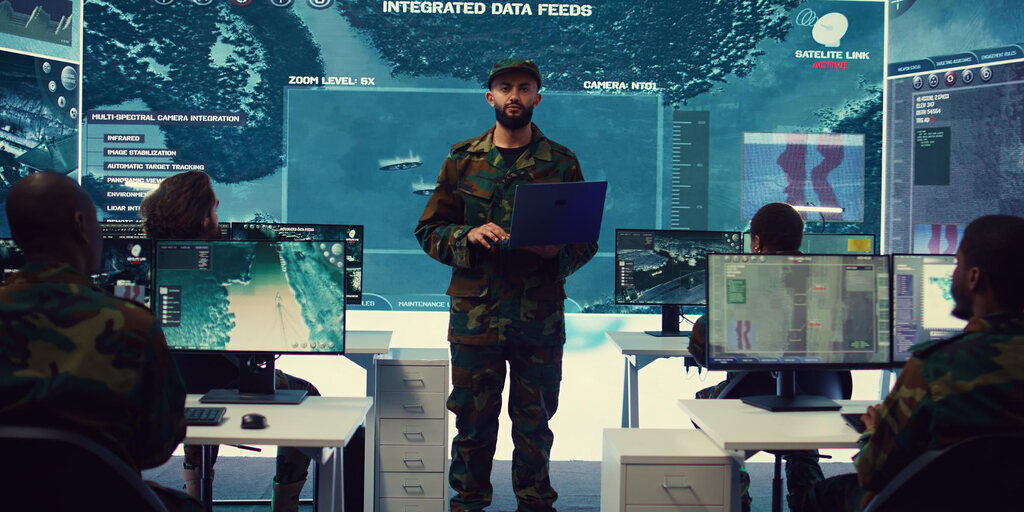 Military personnel participate in a security training session, analyzing real-time integrated data feeds on multiple screens to enhance situational awareness and decision-making.