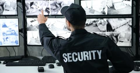 Security guard in surveillance room pointing at monitor